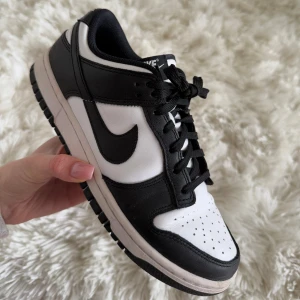 Nike Dunk Low svartvita sneakers - Säljer ett par klassiska Nike Dunk Low sneakers i svart och vitt. Skorna har svart swoosh, snörning och låg profil. Perfekta för dig som gillar streetwear och vill ha en stilren look.