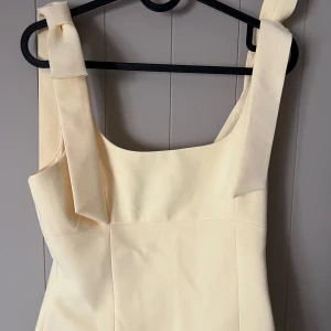 Gul croppad linnetopp med knytband - Söt ljusgul croppad linnetopp med breda axelband som knyts till rosetter. Toppen har en fyrkantig urringning och är perfekt för varma dagar. Köpt på Zara i Nice!