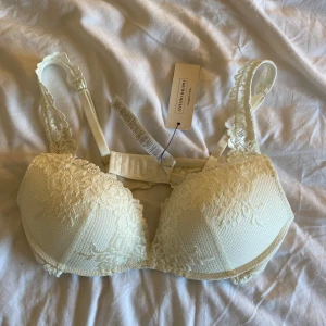 Vit spets-bh från intimissimi - Jättefin elegant vit bh från Intimissimi med vacker spetsdetalj och vadderade kupor. Axelbanden är justerbara och dekorerade med spets. Perfekt för dig som vill ha något extra fint under kläderna. Storlek 75C aldrig använd och prislappen kvar, säljer då jag vill köpa en annan modell!💗