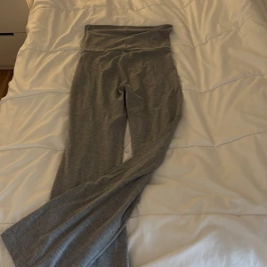 Grå mjukisbyxor från Gina Tricot - Grå mjukisbyxor från Gina Tricot med bred, vikt linning och raka ben. Byxorna är tillverkade i mjukt bomullsmaterial och har en enkel, stilren design utan synliga detaljer eller mönster.