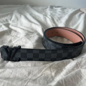 Svart rutigt bälte från Luviton - 115 cm. Snyggt Luviton bälte i svart med rutigt mönster och svart spänne. Bältet har beige insida och har tydlig Luviton logga. Perfekt accessoar för att maxa din outfit. Nästan helt oanvänd och helt ren. PRISET KAN DISKUTERAS.