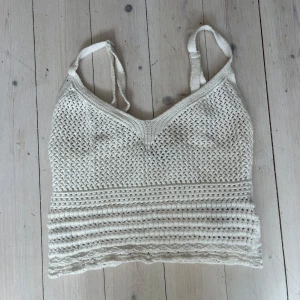Vit stickad stickad linnetopp - Säljer en vit stickad croppad linnetopp med smala axelband och v-ringning. Toppen har ett fint mönster och är perfekt för varma dagar.
