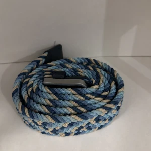 Flätat bälte i blå toner från ONEWEAR - Snyggt flätat bälte i olika blå nyanser och beige, med silverfärgat spänne och detaljer i mörkblått skinn. Perfekt accessoar för att lyfta din outfit med lite färg och stil.