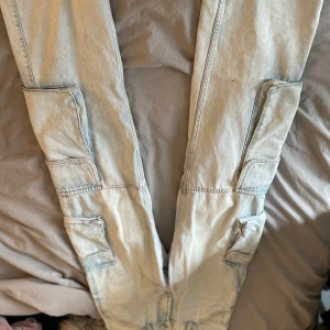 Ljusblå cargopants från ZARA - Säljer ett par ljusblå cargopants från ZARA med flera stora fickor längs benen. Byxorna har en avslappnad passform och är perfekta för en trendig streetstyle-look. Midjan är normal och materialet är klassisk denim.