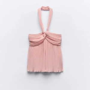 Ljusrosa plisserad halterneck topp - Säljer en ljusrosa halterneck topp med plisserat tyg och twistad detalj framtill. Toppen har en luftig och elegant känsla med breda band som knyts runt nacken. Perfekt för varma dagar eller när du vill känna dig extra fin. Obs dragkedjan är lite trög annars inga defekter❤️