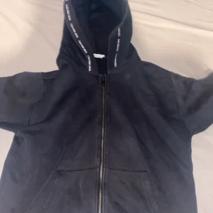 Svart hoodie från Calvin Klein  - Säljer en svart hoodie från Calvin Klein med dragkedja framtill och huva med logotypdetaljer. Tröjan har långa ärmar och ribbade muddar. Klassisk och stilren design med liten CK-brodyr på ärmen. Inte bästa kvaliten men ändå fin!