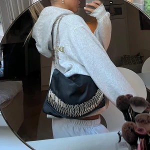 Svart axelväska med kedja  - Snygg svart axelväska i skinnimitation och silvriga detaljer.