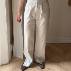 Vida kostymbyxor  - Snygga vita/beige kostymbyxor från lager 157. Hög midja och vida ben. Byxorna har pressveck framtill. Stl XS🤎