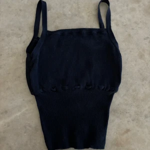 Mörkblå ribbad topp Brandy Melville - Säljer en mörkblå ribbad linnetopp från Brandy Melville med smala axelband och knytning i midjan. Toppen är stretchig och sitter snyggt på kroppen, passar xxs-m beroende på hur man vill att den ska sitta. Perfekt att styla till jeans eller kjol!
