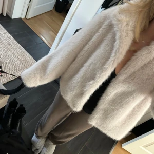 Ljusbeige pälsjacka - Säljer en fluffig och mjuk ljusbeige pälsjacka med lång ärm. Jackan har en rak och lite oversized passform och är perfekt för att ge en lyxig känsla till din outfit. Köpt för 899kr, endast använd 2-3 gånger men inte någon form av skada eller tecken på användning.