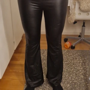 Skinnbyxor i bootcut - Säljer ett par svarta bootcut byxor i skinnimitation med resår i midjan. Storlek - 37