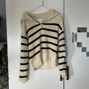 Beige och svart randig stickad tröja från Monki - Säljer en beige stickad tröja från Monki med svarta horisontella ränder. Tröjan har dragkedja framtill, krage och långa ärmar. Perfekt för lager-på-lager och chill dagar. Supermjuk och skön att ha på sig! Ganska dammig