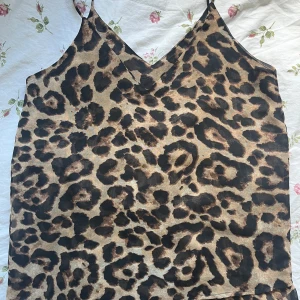 Leopardmönstrad linnetopp från My Jewellery - Säljer en snygg leopardmönstrad linnetopp från My Jewellery. Toppen har tunna axelband och v-ringning, perfekt för att sticka ut med ett djurmönster. Materialet känns lätt och svalt mot huden.