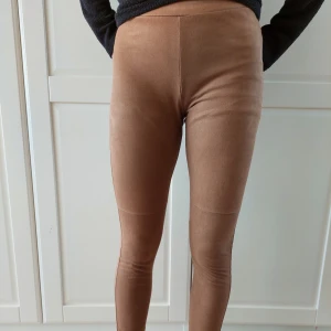 Beige leggings - Beige leggings med mockakänsla fram. Baksidan är av färgmatchande stretchigt tyg. De är supermjuka och bekväma, perfekta för både vardag och mysiga hemmakvällar. Perfekt för höst och vår!