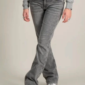 Grå bootcut jeansbyxor med broderade bakfickor - Snygga grå jeansbyxor i bootcut-modell med broderade detaljer på bakfickorna. Jeansen har normal passform och klassisk femficksdesign. 