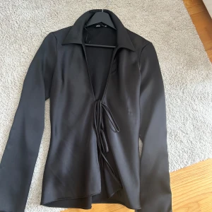 Svart omlottblus med knyt - Säljer en svart omlottblus från Zara med långa ärmar och knyt framtill. 