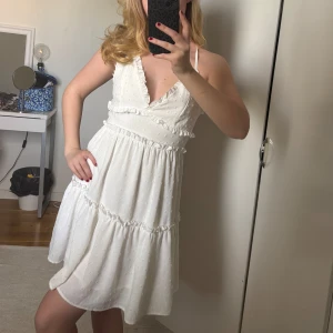 Vit omlottklänning med volang - Söt vit kortklänning🤍 Klänningen har volangdetaljer samt markerad midja och v-ringning. Perfekt för sommaren eller studenten.