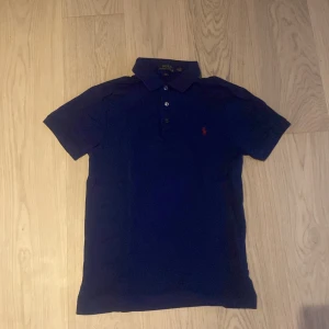 mörkblå ralph lauren piké  - Stilig Ralph Lauren piké i mörkblå ! 💙✨  Säljer en helt  ny piké från Ralph Lauren, endast använd ett fåtal gånger . 👕💫 Tröjan är i perfekt skick utan tydliga defekter och är gjord av 100% bomull. 🌱👌 i storlek S för män. Perfekt för både vardagsbruk och lite finare tillfällen! 🎉🥳   Pris kan diskuteras. 💰 Skicka ett meddelande om du är intresserad! 📩😊