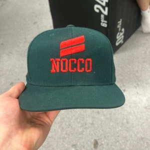 Grön keps från NOCCO - Mörkgrön keps med röd broderad NOCCO-logga framtill och #NOCCO på sidan. Klassisk rak skärm och justerbar passform. Perfekt accessoar för dig som gillar sportig stil. En sjukt limiterad och sällsynt keps från ett utav de senaste nocco släppen. Pris går att diskutera 