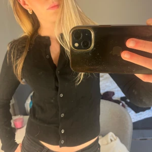 Svart kofta från H&M - Säljer en svart, klassisk kofta från H&M i storlek XS. Koftan har rund halsringning, långa ärmar och knäppning framtill med svarta knappar. Perfekt att styla till olika outfits och enkel att matcha. Om du undrar något är det bara att fråga!!💗💗💗