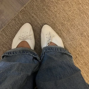 Vita ballerinaskor med snörning från Madonna - Säljer ett par vita ballerinaskor från Madonna med snörning framtill och spetsig tå. Jag ÄLSKAR dom och tycker dom är sååå snygga men tyvärr är dom en aning för små för mig. 