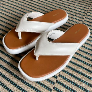 Vita sandaler från & Other stories  - Snygga vita sandaler med bred rem och ljusbrun innersula. De har en platåsula i vitt vit och öppen tå. Perfekta för varma dagar och enkel att matcha med olika outfits. Använda endast en gång. 