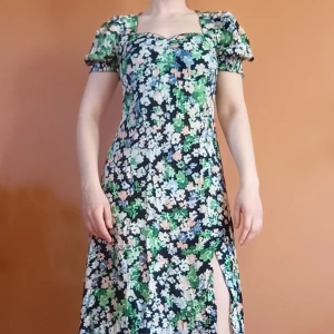 Blommig långklänning - Svart långklänning med blommönster. Klänningen har puffärmar, söt hjärtformad ringning och en slits framtill. Från HM och storlek S 🌸