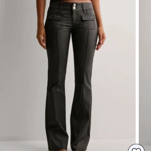 Svarta bootcut-byxor med fickdetaljer - Snygga svarta bootcut-byxor med låg midja. Dom är använda några gånger men fortfarande i nyskick. På Nellys hemsida är som slut. Nypris: 699kr