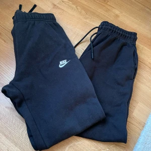 Svarta mjukisbyxor från Nike - Säljer flera par svarta mjukisbyxor från Nike med resår och dragsko i midjan. Byxorna har en klassisk passform och är perfekta för chill eller träning. Nike-logga broderad på ena benet. Mjukt och bekvämt material.