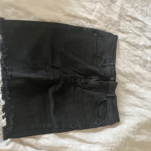 Svart jeanskjol från Vero Moda. - Svart jeanskjol från Pieces med fransad nederkant och klassiska fickor fram och bak. 