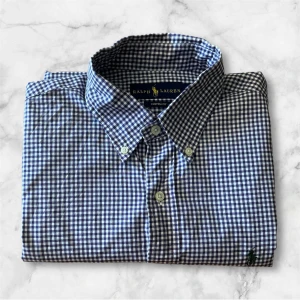 Fin klassisk skjorta från Ralph Lauren - Säljer en klassisk lilarutig skjorta från Ralph Lauren i modellen Custom Fit. Skjortan har lång ärm, knappar framtill och button-down krage. Perfekt för dig som gillar stilrena och tidlösa plagg. Liten broderad logga på bröstet.