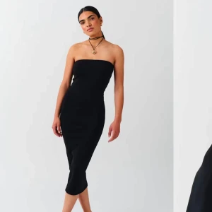 Svart axelbandslös långklänning - Säljer en stilren svart axelbandslös långklänning med tight passform. Klänningen har en minimalistisk design och är perfekt för dig som gillar en enkel men snygg look. Passar till många olika tillfällen och är lätt att styla med accessoarer. Från Gina Tricot. Aldrig använd utan köpte den ifrån vinted och dem passade inte mig så där av säljer jag den. 