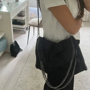 Svart axelväska med kedjedetaljer - Säljer denna väskan. Står ej märke i och köpte för flera år sen.