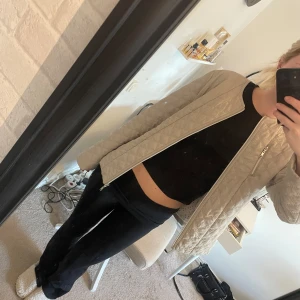 Beige quiltad jacka  - Snygg beige quiltad jacka från Isolde med  dragkedjefickor. Jackan har raka ärmar och en stilren look som passar perfekt till lager-på-lager. Lätt vadderad och med diskret mönster i tyget. Nypris 800