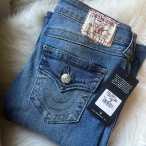 True Religion Joey Low Rise Flare Jeans - Säljer ett par blå True Religion Joey jeans med låg midja och utsvängda ben. Storlek W25, aldrig använda! Nya med etikett kvar, säljer pga att jag nt gillar färgen och för att dom är för stora! 