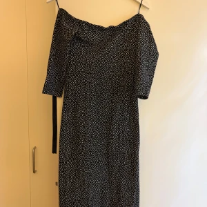 Svartvit prickig långklänning offshoulder från Zara - Supersnygg svart långklänning med vita prickar från Palua Collection Zara. Offshoulder-modell med trekvartsärm och knytband i ryggen som ger en cool detalj. Klänningen har en figurnära passform och är perfekt för dig som gillar att sticka ut.