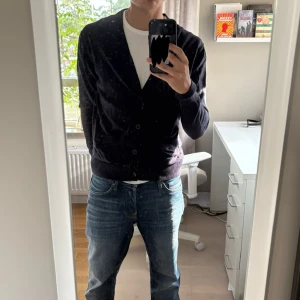 Mörkblå manchesterkofta med knappar - Säljer en mörkblå kofta i mjuk manchester med knappar framtill och två fickor. Koftan har lång ärm och ribbade muddar vid ärmslut och nederkant. Perfekt att slänga över en t-shirt för en chill och stilren look.