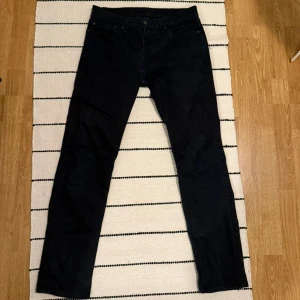 Levi's 511 svarta jeans - Säljer ett par svarta Levi's 511 jeans med klassisk femficksdesign och smal passform. Jeansen har en mörk tvätt, diskret Levi's-lapp bak och är tillverkade i mjukt bomullsmaterial med lite stretch för extra komfort.