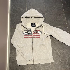 Grå hoodie från Lexington - Tja säljer nu min Snygga ljusgrå hoodie från Lexington, den är i mycket bra skick. Framsidan har ett tryck av Amerikas flagga som gör hoodien mycket snygg. Hör av vid intresse