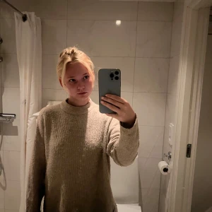 Beige stickad tröja med hög krage - Mysig beige stickad tröja med hög krage och långa ärmar. Tröjan har en relaxed fit och är perfekt för lager-på-lager. Ribbad struktur som ger en snygg och enkel look. Passar dig som gillar en stilren och chill vibe.