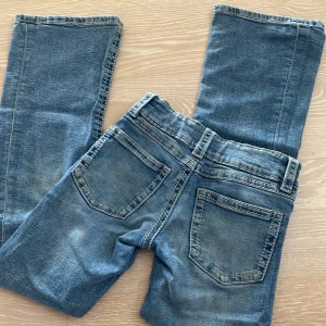 Blå jeans från Gina Tricot stl 146 - Snygga blå jeans från Gina Tricot i storlek 146. Klassisk femficksmodell med dubbla silverfärgade knappar och bälteshällor. Jeansen har raka ben och ljusa slitningar för en cool look. Perfekta till vardags med en hoodie eller t-shirt.
