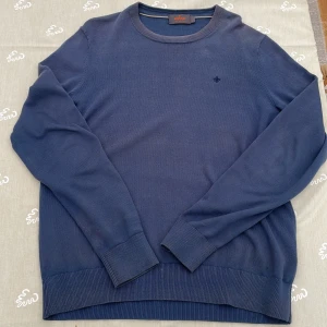 Blå bomullströja från Morris S - Säljer en stilren blå tröja från Morris i 100% pima bomull. Tröjan har rund hals, ribbade muddar och diskret broderad logga på bröstet. Perfekt för dig som gillar klassisk och enkel stil. Priset är ej hugget i sten