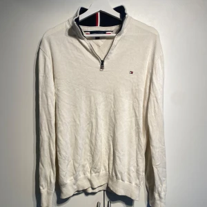 Vit half zip tröja Tommy Hilfiger - Vit långärmad tröja från Tommy Hilfiger med half zip och liten broderad logga på bröstet. Tröjan har ribbade muddar och krage med snygga detaljer på insidan. Perfekt för dig som gillar stilren och klassisk look. Storlek M. Välanvänd men i fint skick. Nypris 1700kr. Fler bilder i DM! 