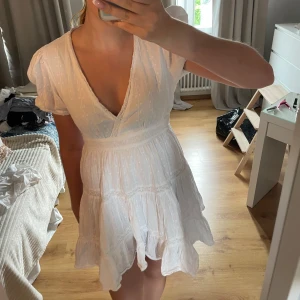 Vit omlottklänning med volang - Supersöt vit kortklänning med omlott och v-ringning. Klänningen har puffiga korta ärmar, volangkant nertill och diskret prickigt mönster i tyget. Perfekt för sommarens alla tillfällen och ger en romantisk vibe. Skriv för fler bilder eller vid frågor! Pris  går att diskutera!💕