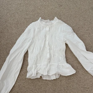 Smock blus från Nelly  - Säljer denna underbart fina blus från Nelly med knappar. Den passar bra till basic outfits och mer stilren look. Säljer blusen eftersom den är lite för kort vid magen på mig. Använd ca 1-2 gånger.