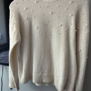 Vit tröja med pärlor  - En så fin vit/cremefärgad tröja med långa ärmar och som har vita pärlor på sig! Tröjan är från H&M i storlek Xs men skulle gissa på att den också passar storlek S!🥰inga defekter förutom lite damm på tröjan annars är tröjan i sig fint skick då den bara används ett fåtal gånger. Den är även lite lite nopprig som inte syns så mycket. Hör av er för fler frågor eller bilder!💕