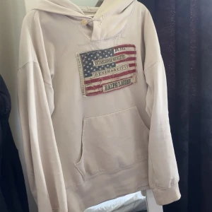 Vit  hoodie Ralph Lauren Denim & Supply - Säljer nu min RL hoodie med en snygg usa flagga som detalji. Hoodie är i super bra skick pch hjälper verkligen din stil sticka ut. Jag vill ha runt 1399 för den men pris är självklart diskuterbart. Tröjan är i topp skick med inga defekter. Strl S-M