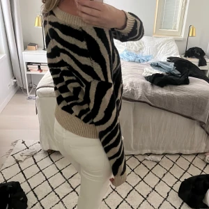Zebramönstrad stickad tröja beige/svart - Säljer en stickad tröja med zebramönster i beige och svart. sömmen är sprucken under armen (bild 4) som går lätt att fixa själv