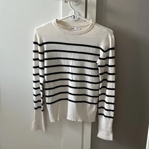 Fin tröja till skolan - Vit långärmad tröja från Sinsay i storlek XS men passar som s  med svarta horisontella ränder. Tröjan har ribbade muddar med cool slitsdetalj vid ärmsluten och är gjord i ett mjukt, stickat material. Perfekt för dig som gillar en klassisk men trendig look.