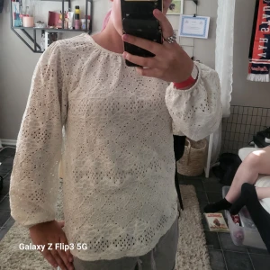 Vit spetsblus med puffärm - Superfin vit blus i spets med lång puffärm och rund hals. Blusen har ett vackert broderat mönster och är lätt transparent. Perfekt för dig som gillar feminin stil. Snygg att styla med jeans eller kjol!